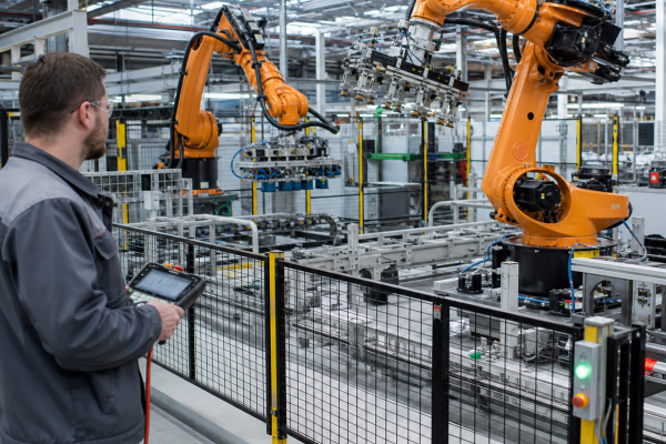 Technician observing robotic arms on a production line